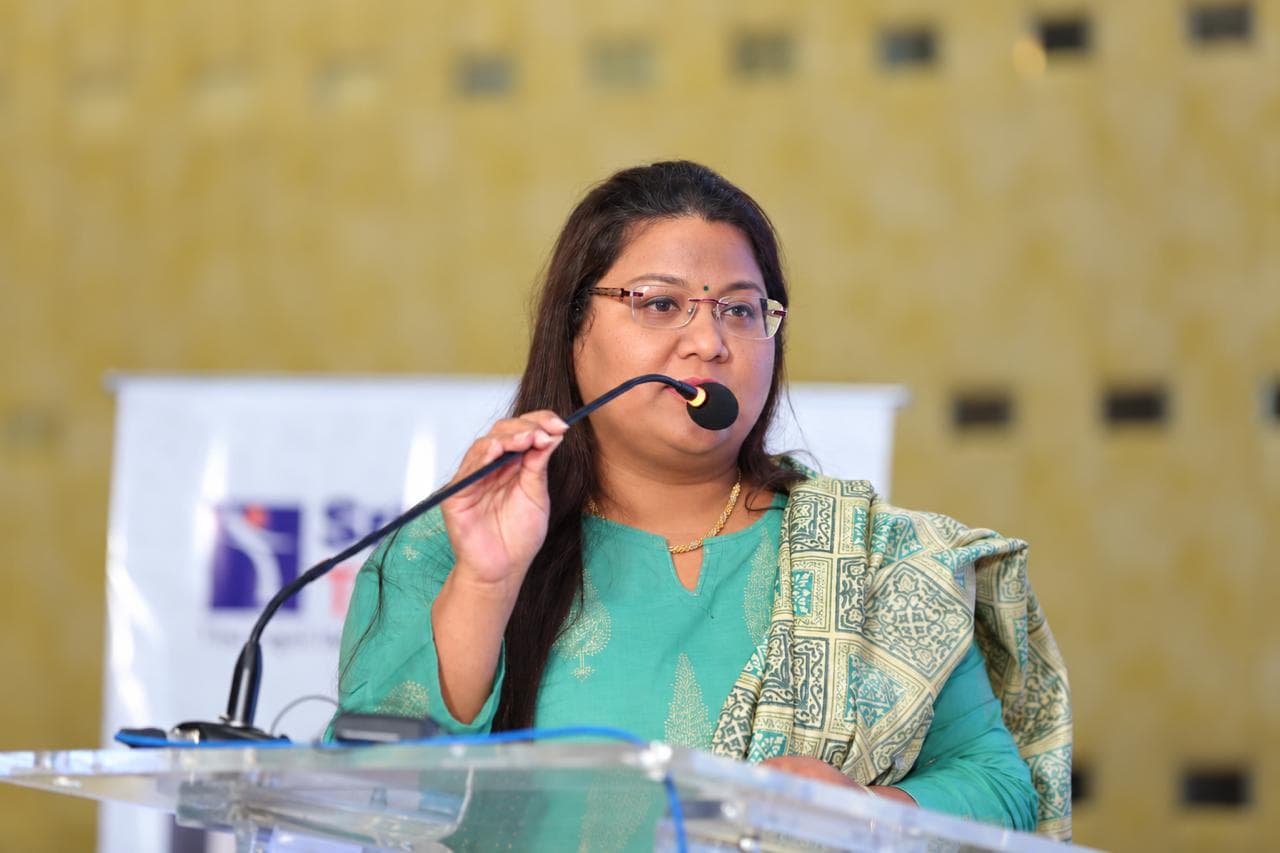 Pushpa Valli speaking at a lectern during an education event.