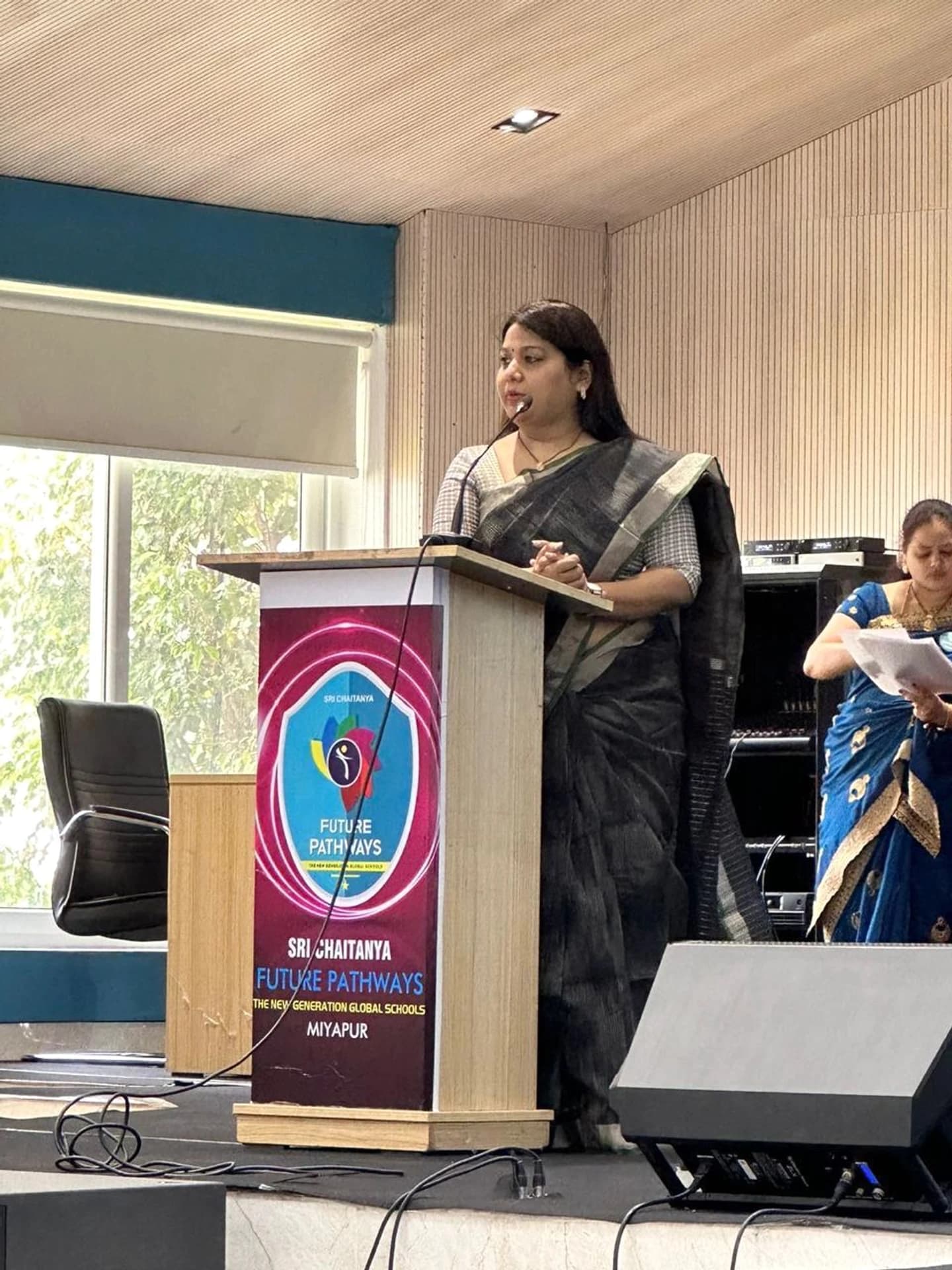 Pushpa Valli addressing an audience from the Sri Chaitanya Future Pathways podium.